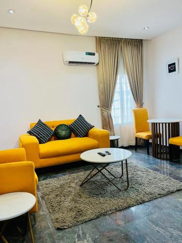 a living room with a yellow couch and a table at Diaggello Homex Apartment in Lekki