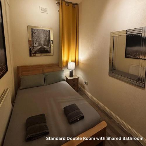 a small bedroom with a bed and a mirror at Hendham House in Manchester