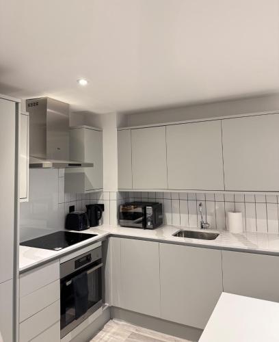 a white kitchen with white cabinets and a sink at Central Birmingham Pool Table Fast Wifi Sleeps Up to 6 Parking nearby in Birmingham