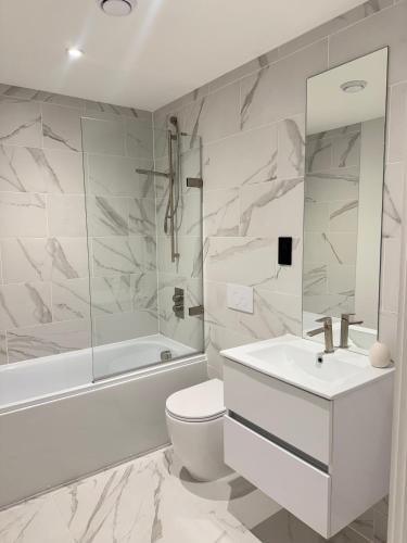 a white bathroom with a tub and a toilet and a sink at Central Birmingham Pool Table Fast Wifi Sleeps Up to 6 Parking nearby in Birmingham
