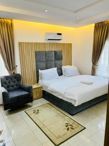 a bedroom with a large bed and a chair at Diaggello Homex Apartment in Lekki