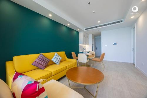 a living room with a yellow couch and a table at Luna Sol Villas - Dedicated Care Until Check Out in Phu Quoc