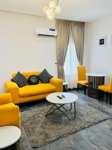 a living room with a yellow couch and a table at Diaggello Homex Apartment in Lekki
