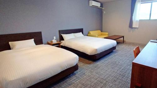 a hotel room with two beds and a yellow chair at Ｓｗｉｍｍｙ Ｉｎｎ Ｏｎａｇａｗａ - Vacation STAY 31622v in Onagawa