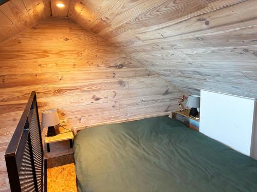 a bed in a room with a wooden wall at Jardin Stan in Chiny