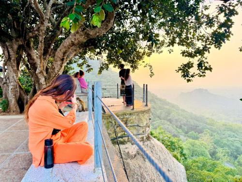 a woman sitting on the edge of a ledge looking at the view at Village Life Mihinthale in Anuradhapura