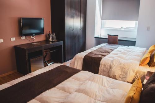 a hotel room with two beds and a television at Hotel Malargue in Malargüe