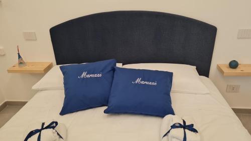 a bed with two blue pillows on it at Maruzzé luxury room in Albori
