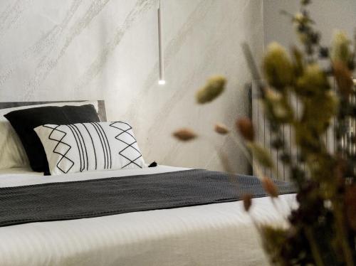 a bed with black and white pillows in a room at Little House AURORA in Melfi