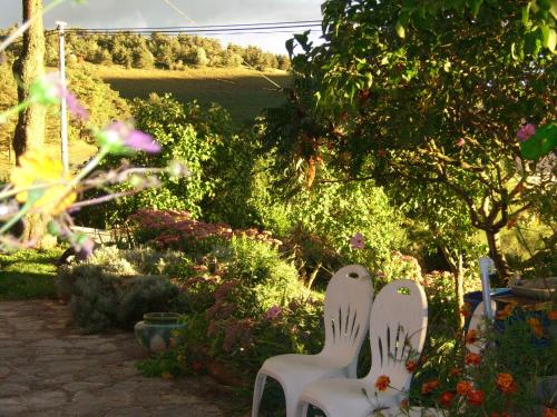 two white chairs sitting in a garden with flowers at Chez Louis chambres d'hôtes à la ferme in La Canourgue