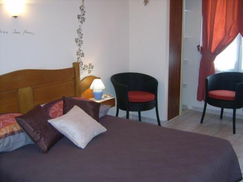 a bedroom with a bed with two chairs and a table at Chez Louis chambres d'hôtes à la ferme in La Canourgue