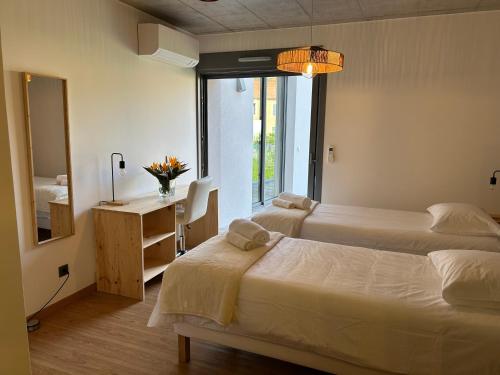 Un dormitorio con dos camas y un escritorio y una ventana. en Villa MARIE, en Fajã da Ovelha