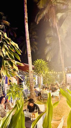 a group of people sitting at tables at a resort at Garden Aroma Palolem, Beachside Hostel & Cafe Bar in Palolem
