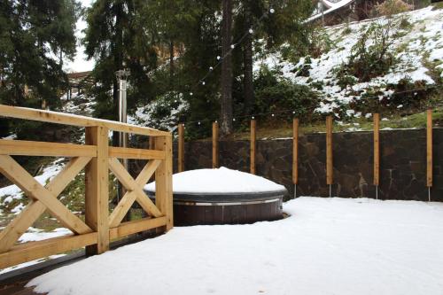 a wooden fence with a snow covered hot tub at Shypit Spa&Resort in Pilipets
