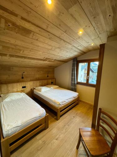deux lits dans une chambre avec un plafond en bois dans l'établissement Le Pré Veillant, à Val Cenis