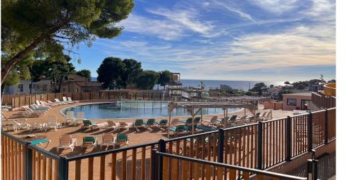 une piscine avec des chaises longues et une clôture dans l'établissement Bungalow Mobil Home Carry-le-rouet, à Carry-le-Rouet