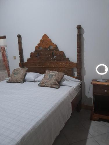 a bed with a wooden headboard and pillows on it at Sweetsop Jamaica Villa and Tour in Montego Bay