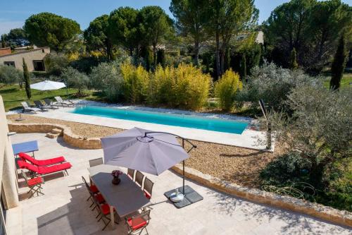 - une vue sur la piscine avec une table et un parasol dans l'établissement Sérénité en Provence, Climatisée, à La Roque-sur-Pernes