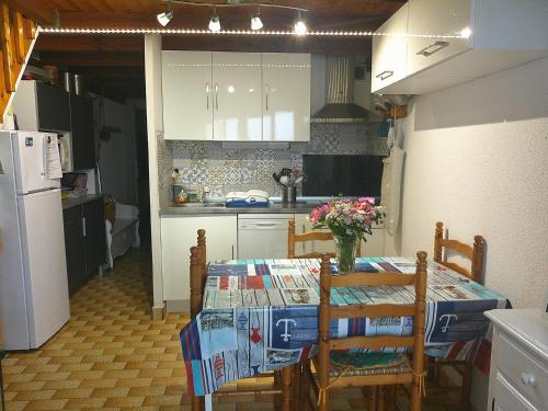 une cuisine avec une table avec des chaises et un réfrigérateur dans l'établissement Bel Appartement Terrasse Vue Mer, à Port-Leucate