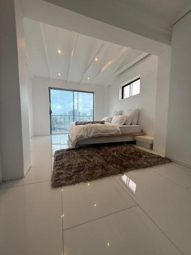 a white bedroom with a bed and a rug at The White House - Zonnebloem in Cape Town
