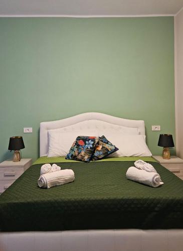 una camera verde con un letto con due asciugamani di Mary's Rooms a Porto Torres