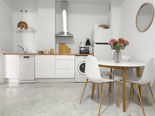 eine Küche mit weißen Geräten sowie einem Tisch und Stühlen in der Unterkunft Apartamento acogedor - piscina - parking in Sevilla