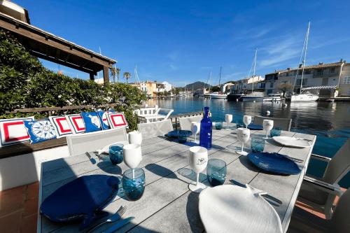 - une table avec des chaises et des verres à vin sur l'eau dans l'établissement Fisherman house - 16m-mooring and a wonderful panoramic, à Grimaud