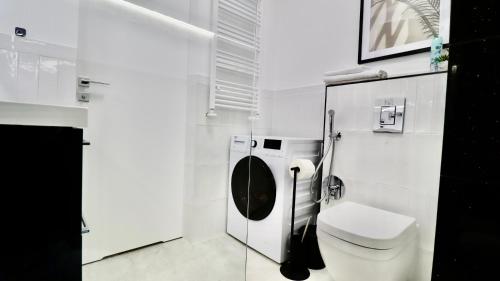 a white bathroom with a toilet and a sink at Apartamenty Jurowiecka 13 in Białystok