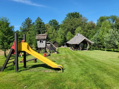 a playground with a yellow slide in a field at Zagroda Krasna in Polańczyk