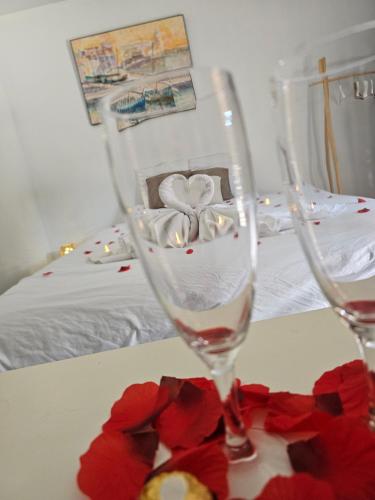two wine glasses sitting on a table with red roses at Résidence du Soleil in Collioure