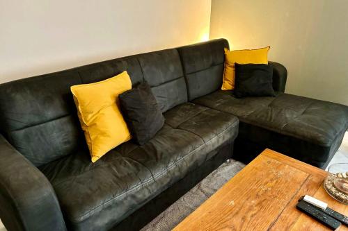 a brown leather couch with yellow pillows on it at Beautiful apartment of 67 m2 near Strasbourg in Bischheim