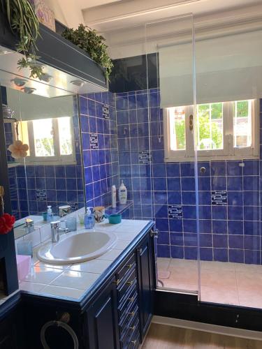 une salle de bain carrelée bleue avec un lavabo et une douche dans l'établissement Chez Martine Côté Cité, à Carcassonne