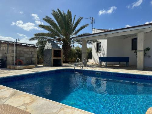 a swimming pool in front of a house with a palm tree at Villa Margarita Latchi in Lachi