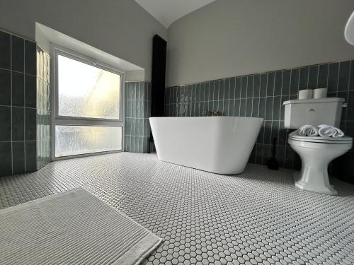 a bathroom with a tub and a toilet and a window at The Round House in Strangford