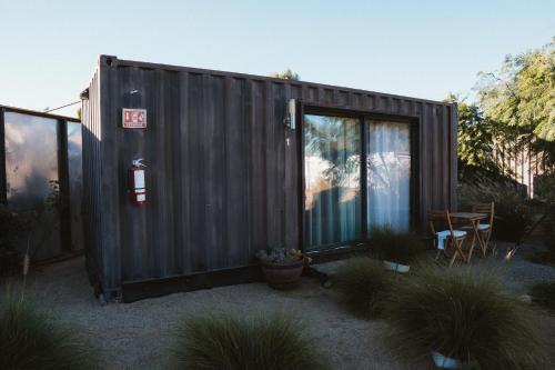 a black shed with a table and a chair at La Finca de Vane in Valle de Guadalupe