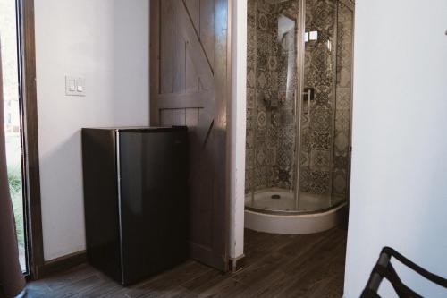 a black refrigerator in a room with a shower at La Finca de Vane in Valle de Guadalupe