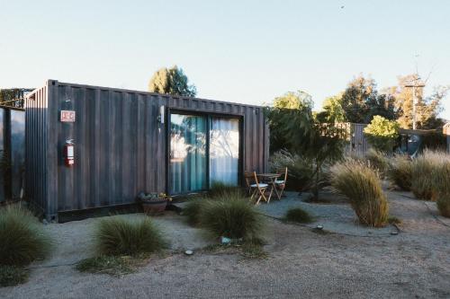 a tiny house in a garden with a chair at La Finca de Vane in Valle de Guadalupe