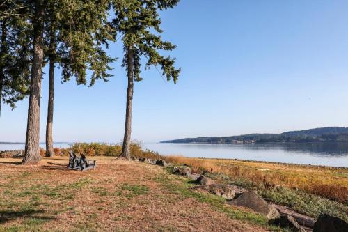 two people sitting on a bench next to a lake at Buckley Bay Beach House in Courtenay