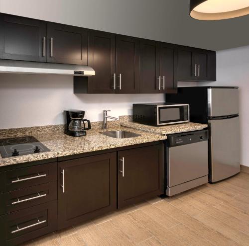 a kitchen with black cabinets and stainless steel appliances at TownePlace Suites by Marriott Sudbury in Sudbury