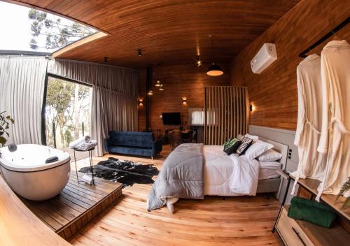 a bedroom with a bed and a tub and a bathroom at Vale Tancon Eco Village Urubici in Urubici