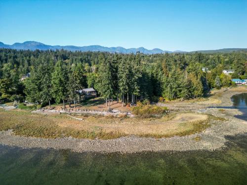 an aerial view of a field with trees and a house at Buckley Bay Beach House in Courtenay