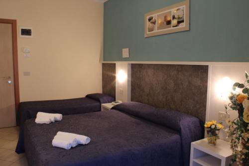a hotel room with two beds with towels on them at Hotel Senyor in Rimini