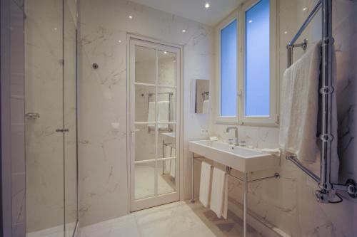 een witte badkamer met een wastafel en een douche bij Relais12bis Bed & Breakfast By Eiffel Tower in Parijs