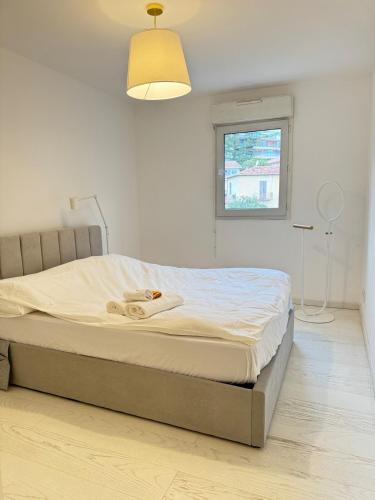 un lit dans une chambre blanche avec une fenêtre dans l'établissement New,mountain & sea view 3 guests with private Garage, à Beausoleil