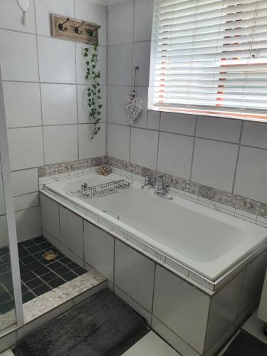 a white bath tub in a bathroom with a window at Moments and Memories house in East London