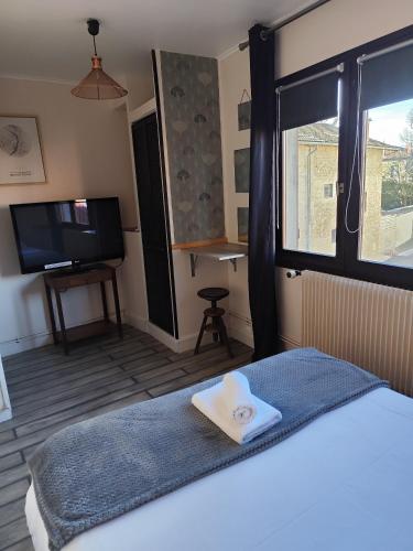 a bedroom with a bed and a flat screen tv at Hotel de la Place in Loyettes