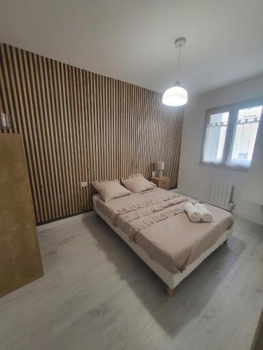 une chambre avec un lit et un mur en bois dans l'établissement Appartement Cosy centre ville, à LʼIsle-sur-la-Sorgue