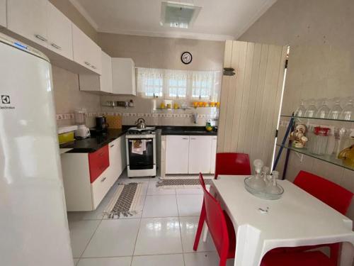 a kitchen with a white table and red chairs at Casa Aconchego Formosa em Praia de Formosa Cabedelo Paraíba in Cabedelo