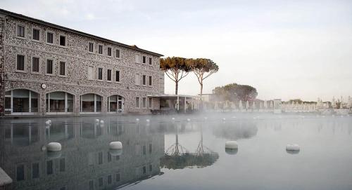 a building sitting on top of a body of water at PODERE TORRICELLE 69B Pancole Gr, seaview infinity pool, jacuzzi, sauna, exclusive villa with 2 bedrooms for 4 - If you total 5 or 6 people there is an independent suite in main villa with private ensuite bathroom, kitchenette and garden dining area in Pancole