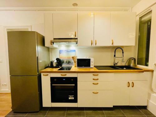 eine Küche mit weißen Schränken und einem grünen Kühlschrank in der Unterkunft Appartement Maridor Porte de Versailles Paris in Paris